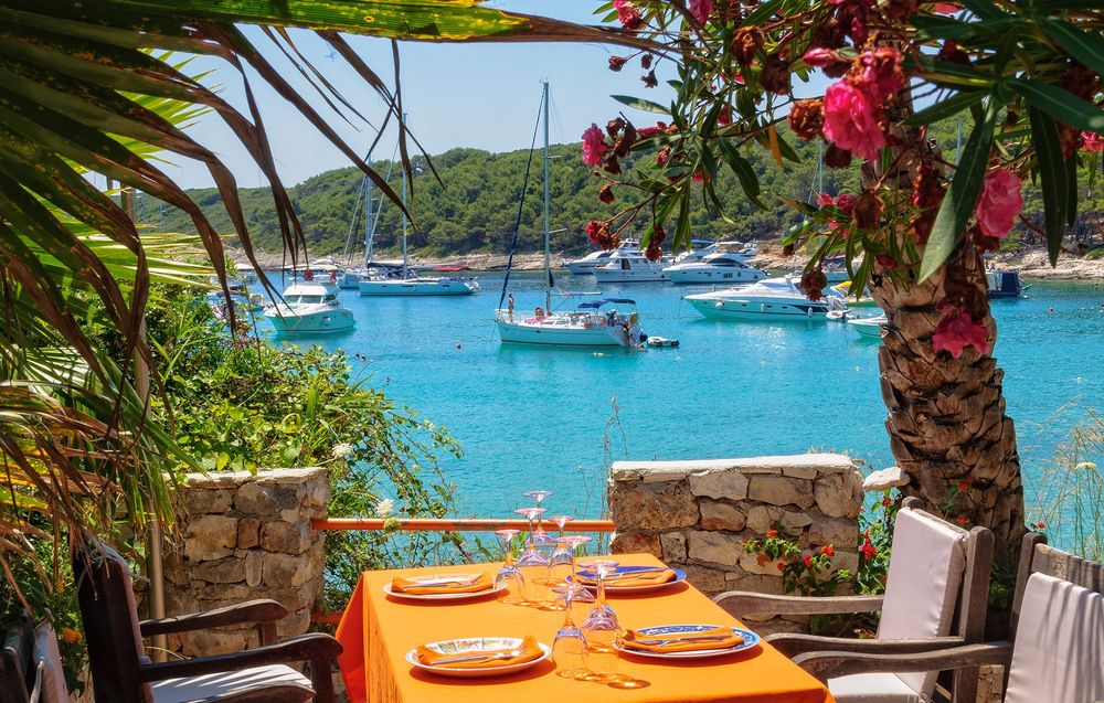Yachts on anchor in Milna Bay photographed from the terrace of a restaurant - Hvar, Croatia © Ikonya/Shutterstock