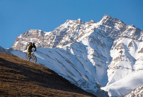 Professional freerider Wade Simmons descending in front of snow-covered mountains on the Annapurna circuit, Nepal